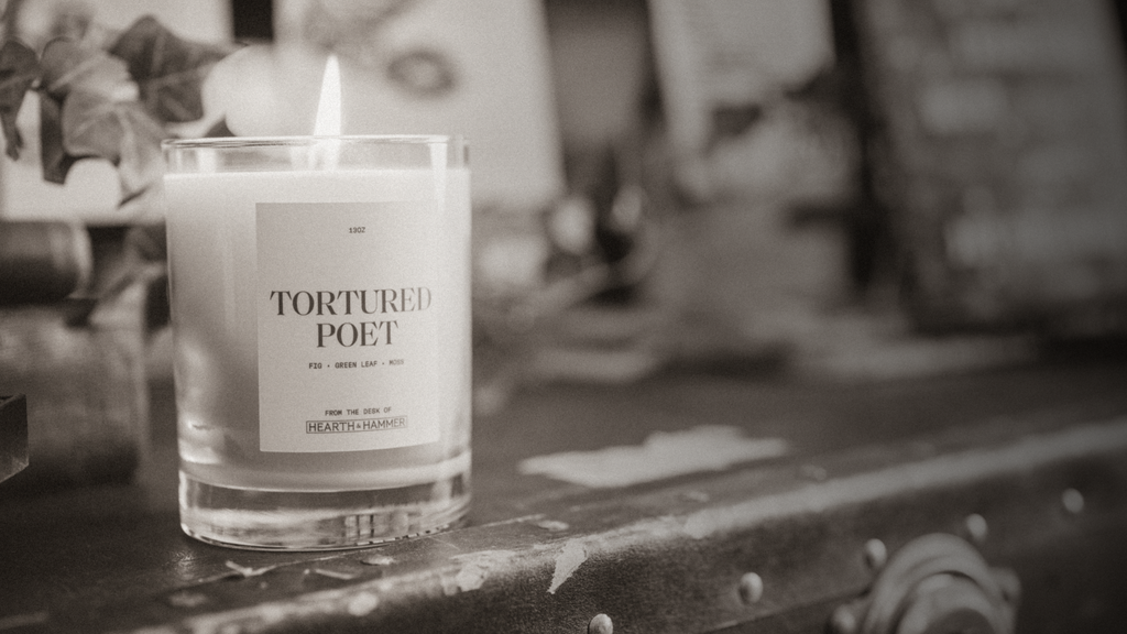 a sepia toned image of a lit candle amongst Taylor Swift ephemera. The candle label reads "Tortured Poet"  