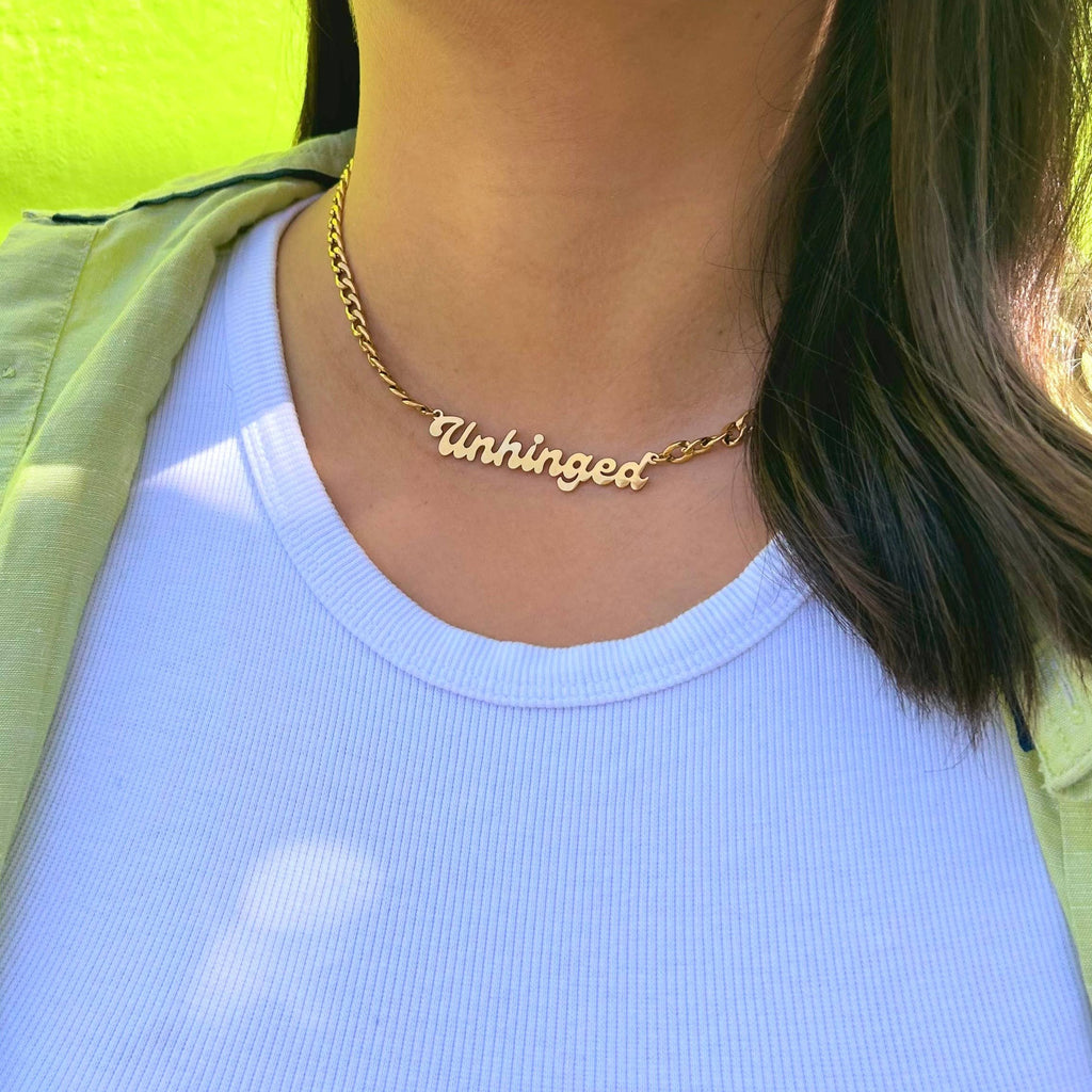 A person wearing the Unhinged Nameplate Necklace with a white tanktop.