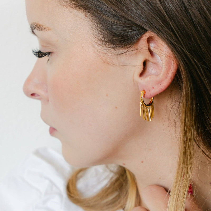 A side view of a person wearing the Fringe with Benefits Earrings in gold.