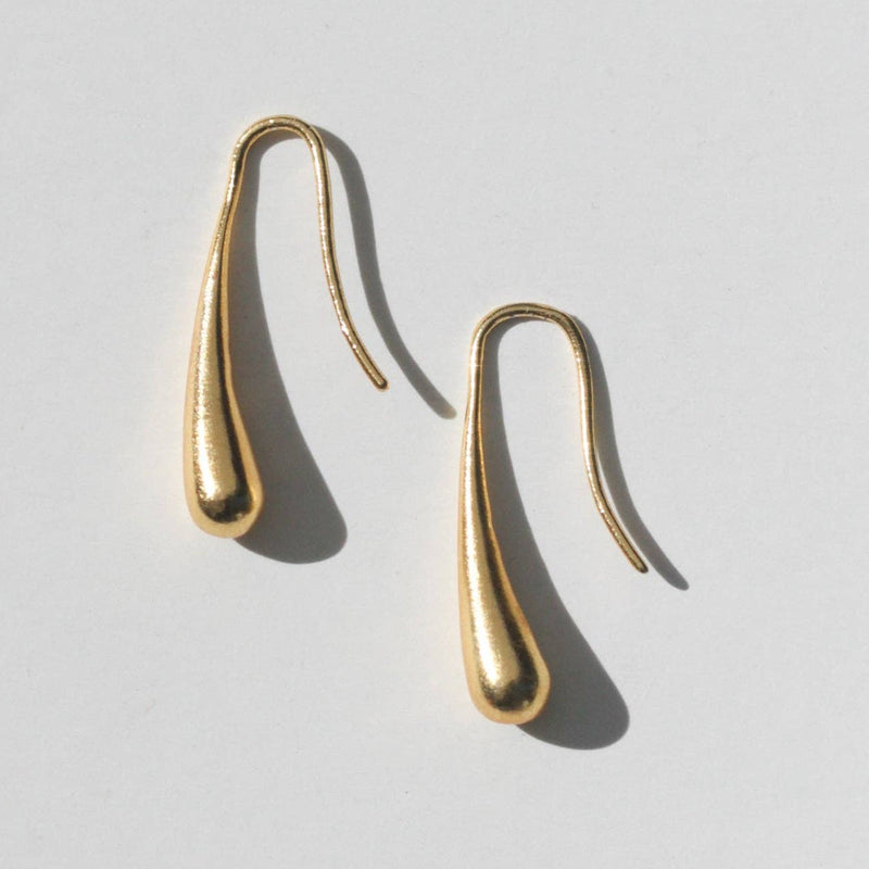 A gold brass fish hook earring that ends in a drop shape.