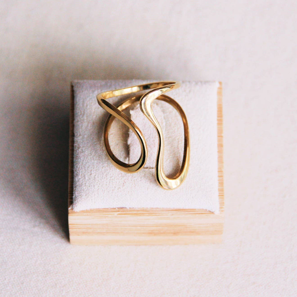 A gold steel ring with a thin wavy band of metal that winds around the finger.