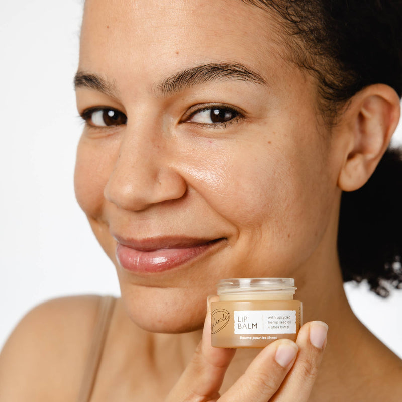 A person wearing the Lip Balm while holding the jar up to their face.