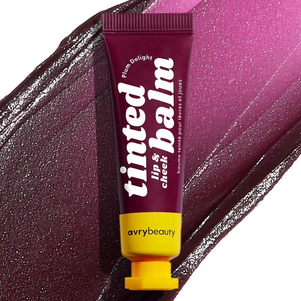 A plum tube with a yellow cap against a spread of Plum Delight Tinted Balm.