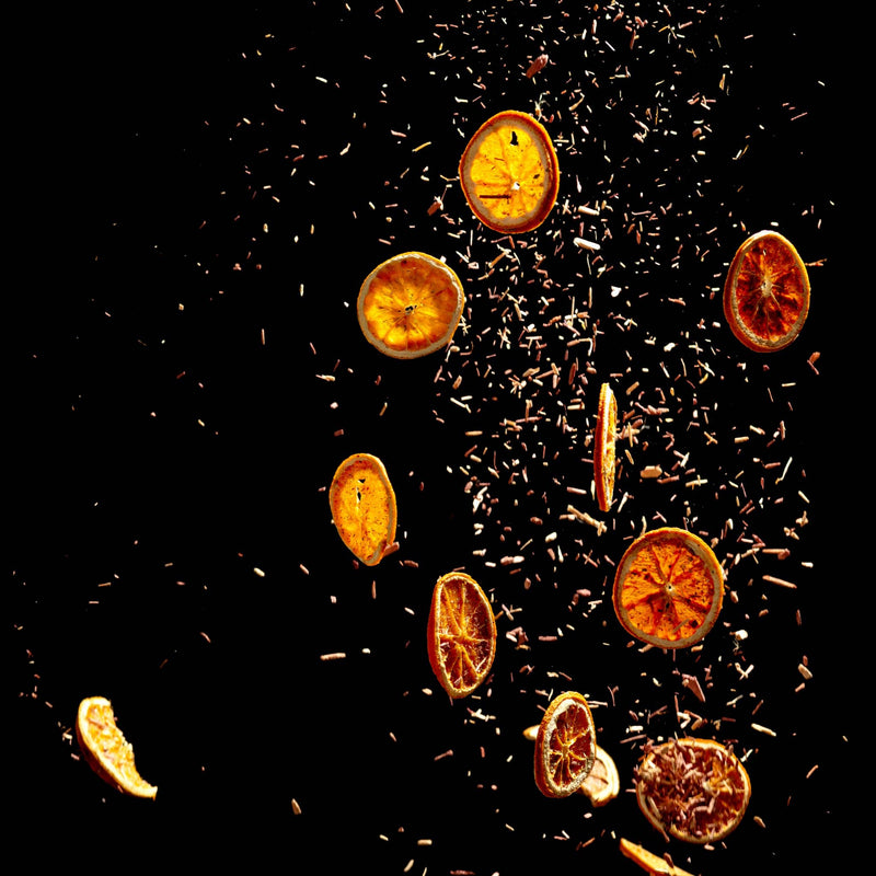 Orange slices and bergamot tea falling in front of a black background.