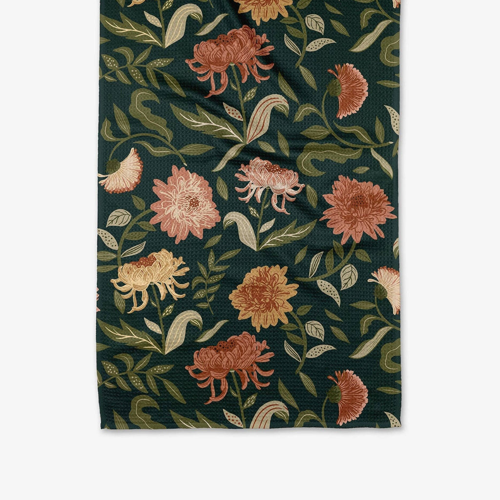 A dark teal tea towel decorated with chrysanthemums and leaves.