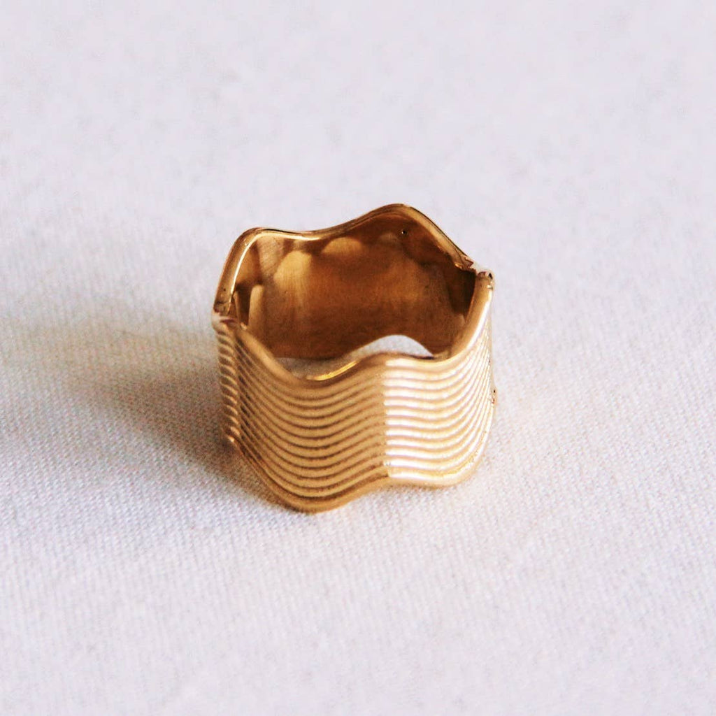 A thick gold stainless steel ring with a wavy striped texture.