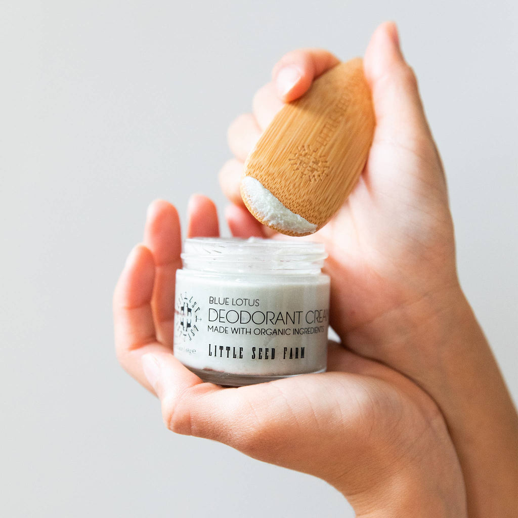 A hand using a Bamboo Deodorant Applicator to scoop out a bit of Blue Lotus Deodorant Cream.