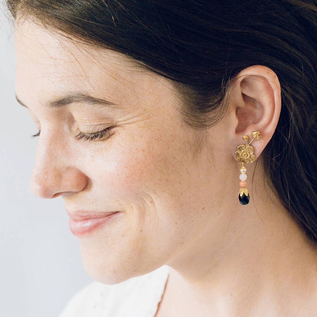 A 3/4 view of a woman wearing the Flower Stud earrings in her lobe.