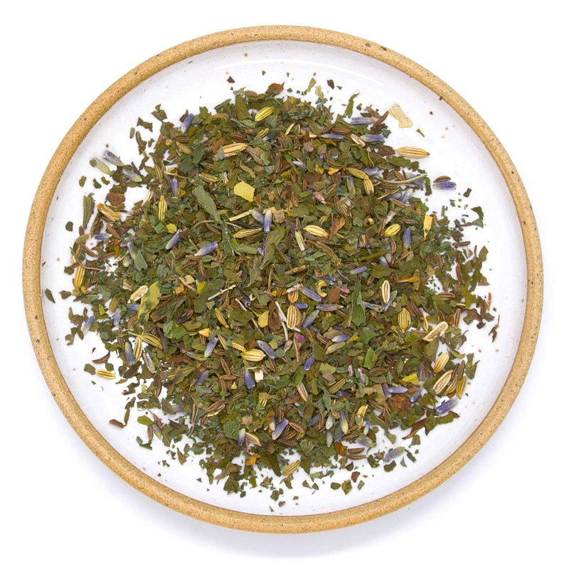 A ceramic plate filled with peppermint, fennel, caraway and lavender tea leaves.