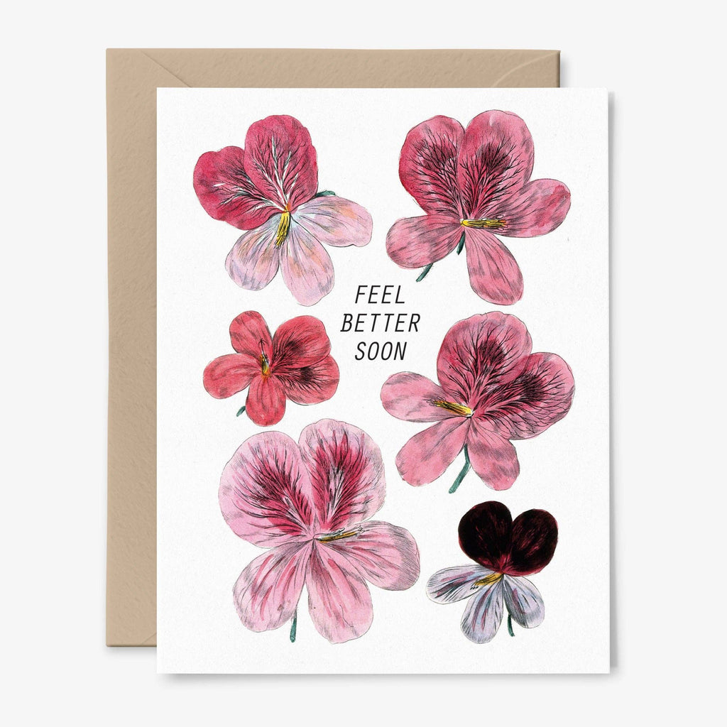 A white card that says "Feel Better Soon" illustrated with pink flowers and a kraft envelope behind.