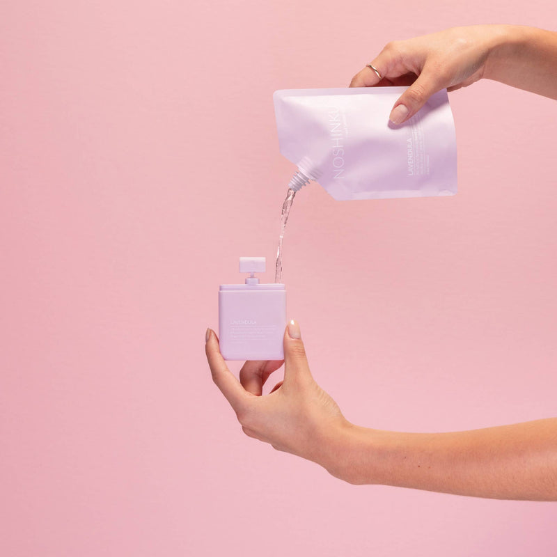 A hand refilling the lavendula hand sanitizer.