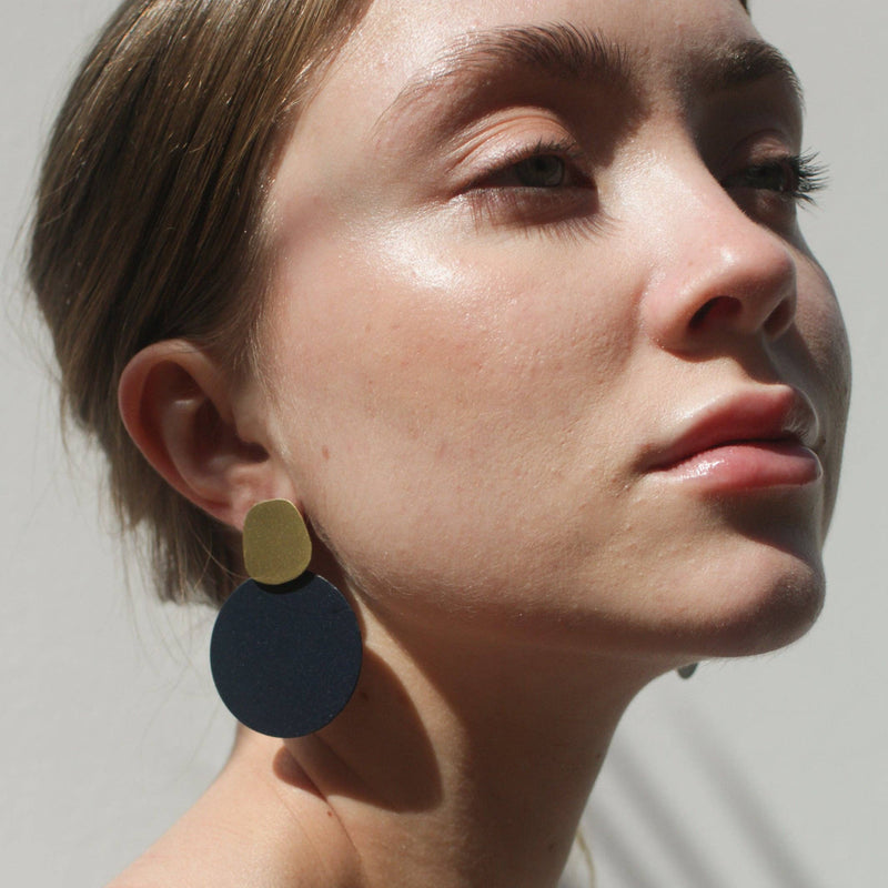 A person wearing the Ultramraine Eclipse Earrings in the sun.