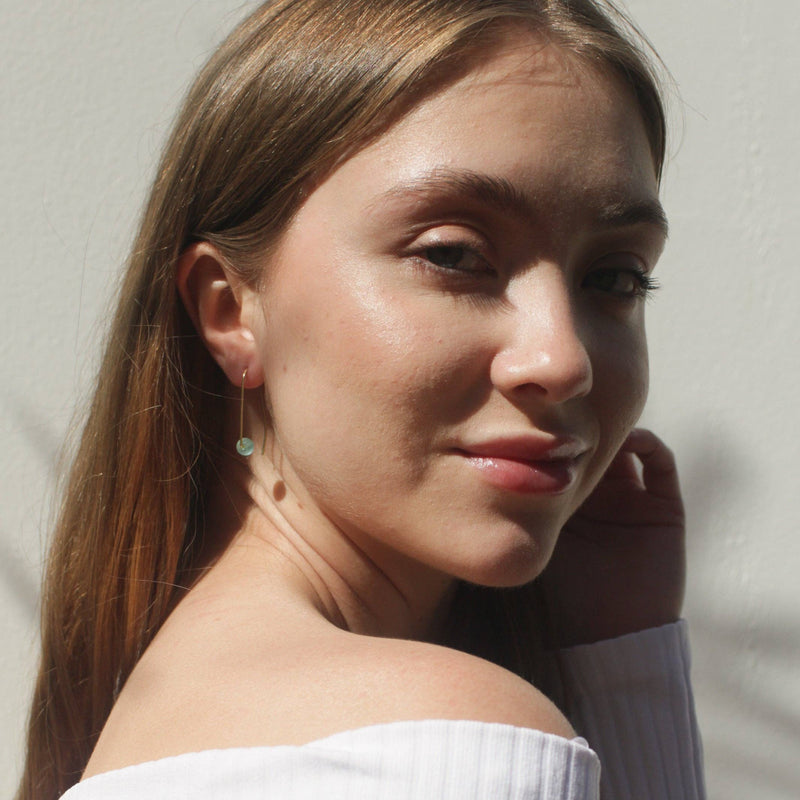  A person wearing the Sea Glass Threader earrings in Aqua with a white off the shoulder top.