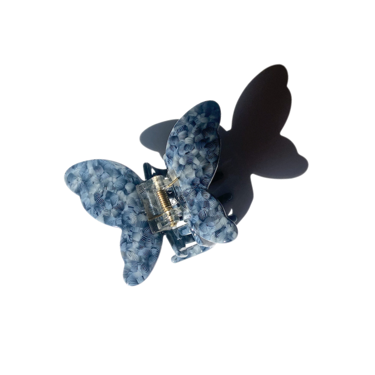 A gray-blue butterfly claw clip patterned with cross hatch circles in the cellulose acetate.