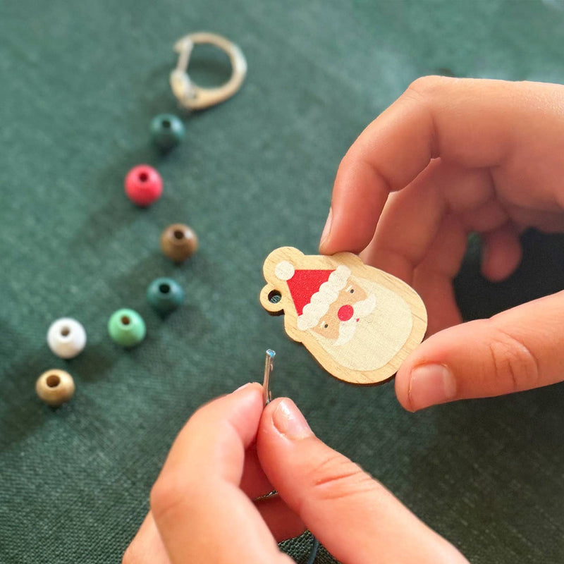 A pair of hands about to thread the string through the santa pendant.