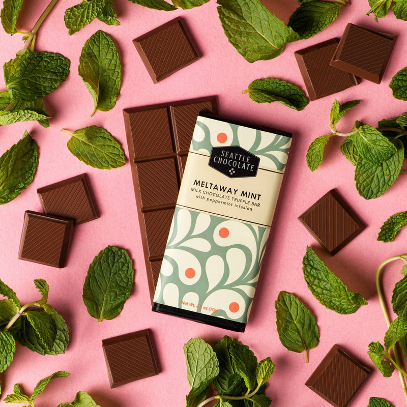 A Meltaway Mint Bar surrounded by squares of chocolate and mint leaves.