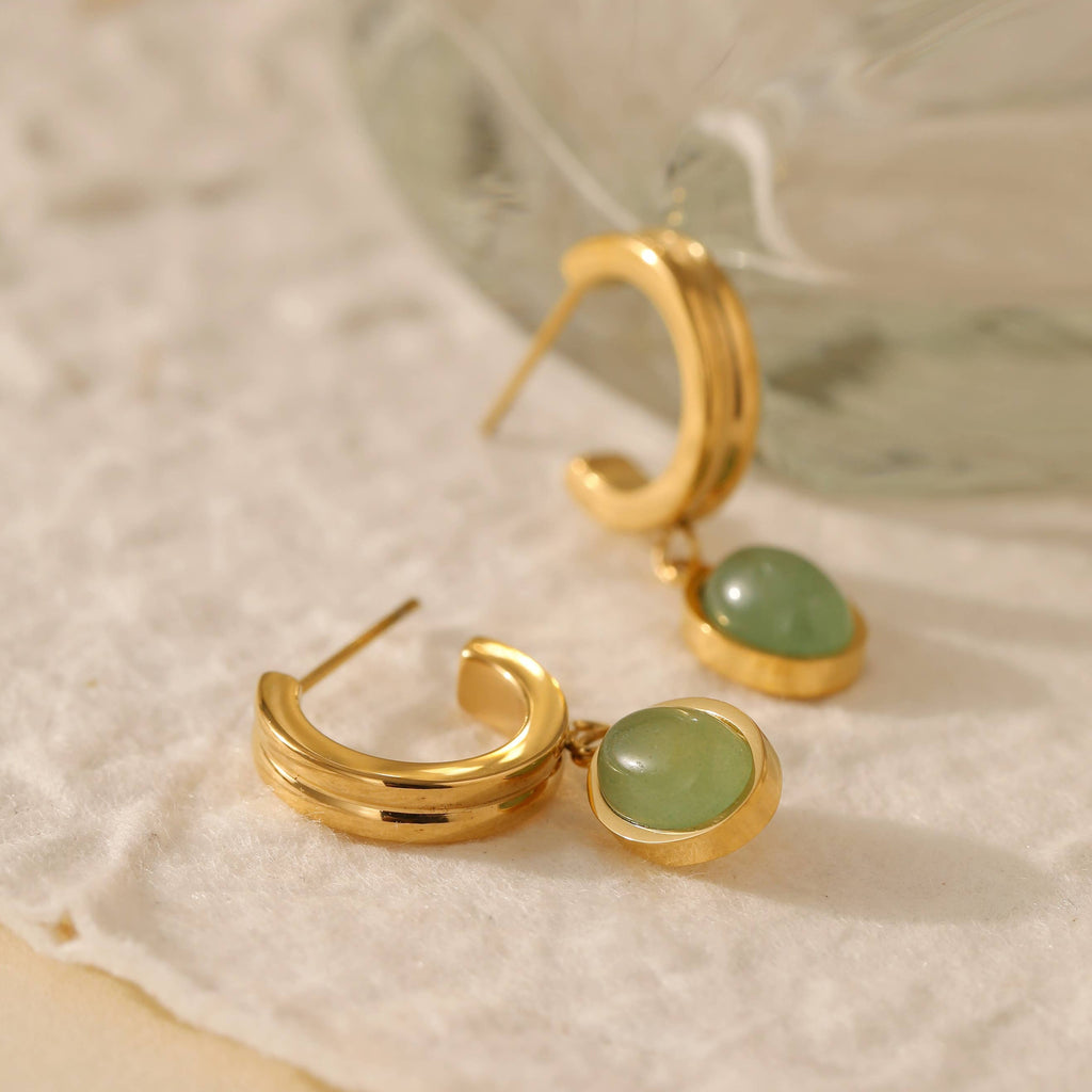 Two gold plated stainless steel huggie hoops with a green aventurine stone encased in gold hanging from the bottom.