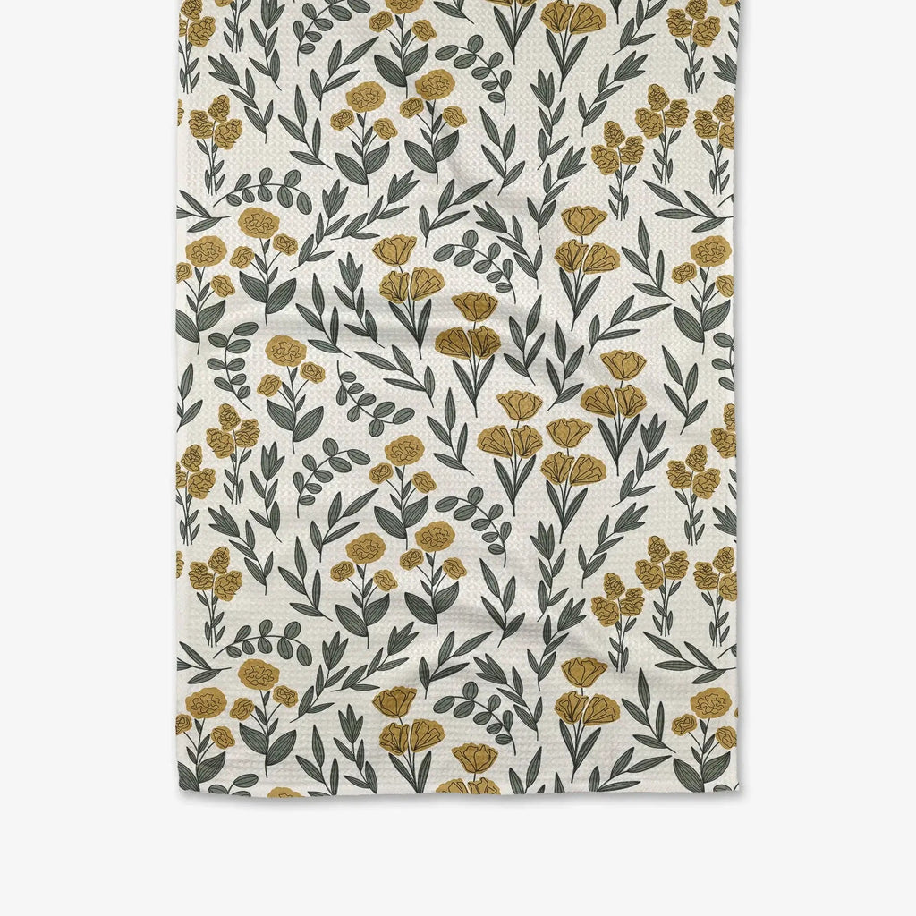 A white towel patterned with yellow flowers and sage green botanicals.