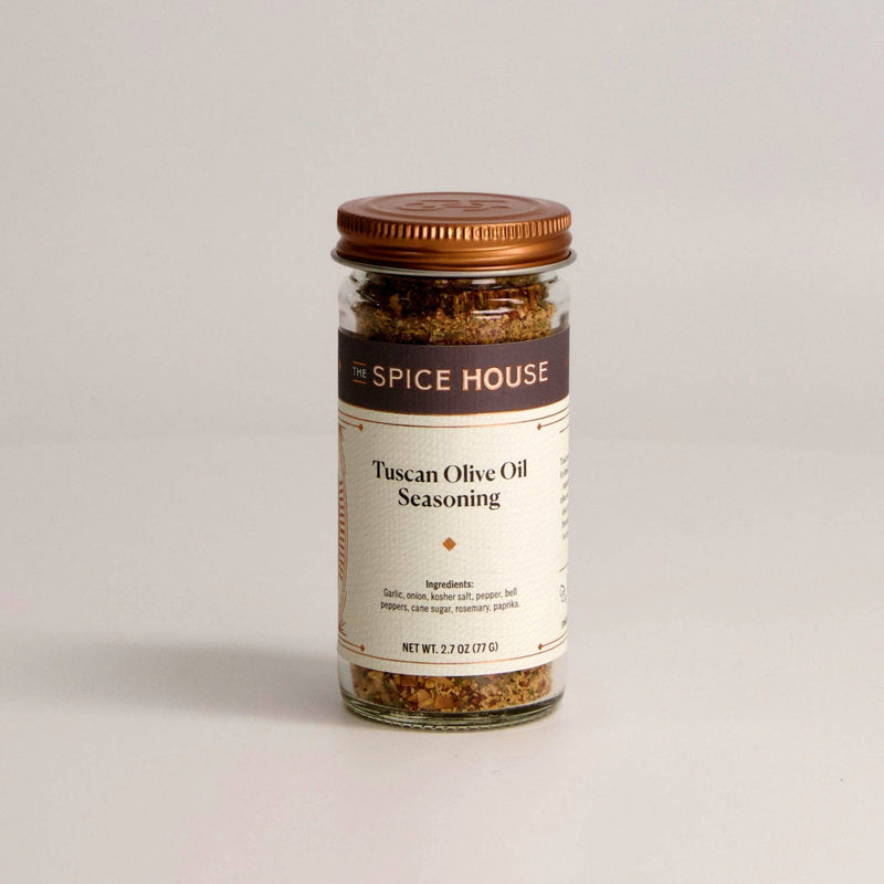 A glass jar of Tuscan Olive Oil Seasoning with a copper lid.