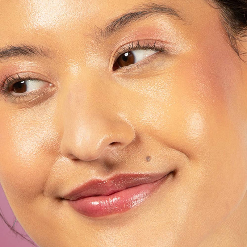 A person with medium tone skin wearing Plum Delight on their eyelids, cheekbones, and lips.