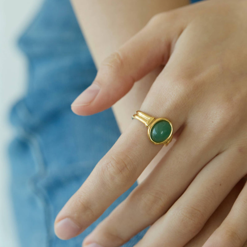 A gold plated stainless steel ring with an oval aventurine stone encased in gold.