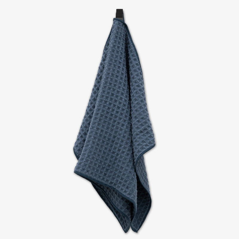 A smokey blue waffle hand towel hanging from a hook.