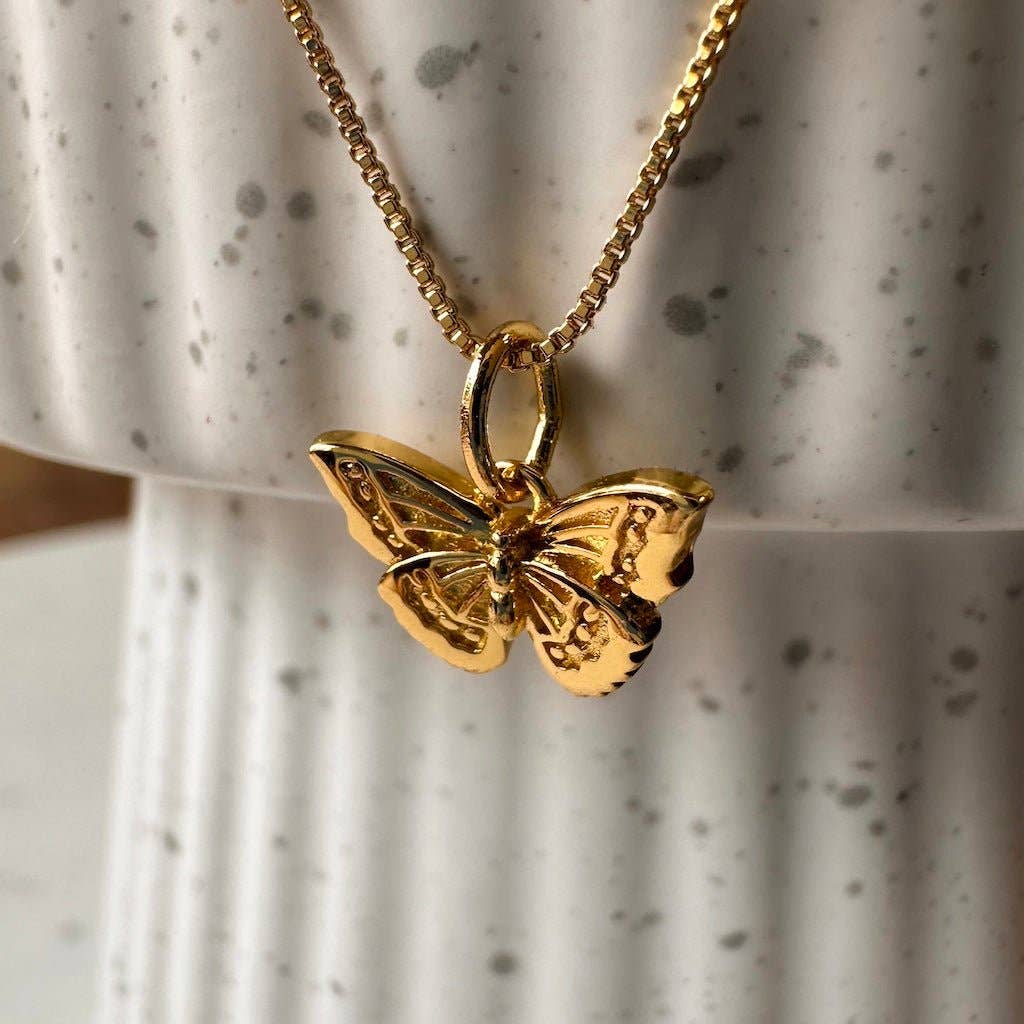 A close-up of a gold plated butterfly pendant on a gold plated chain.