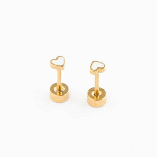 A pair of tiny gold stud earrings with a white enamel heart and flat back posts.