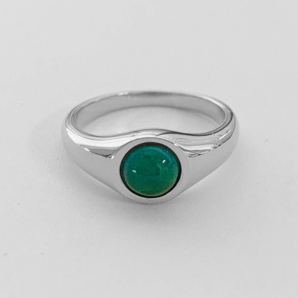 A sterling silver plated ring with a circular teal mood gem inlaid in the center.