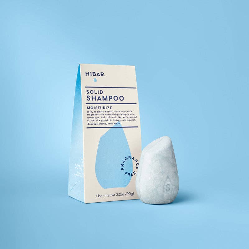 A pale blue fragrance-free moisturize shampoo bar next to its packaging.