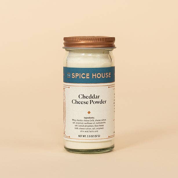 A glass jar of White Cheddar Cheese Powder with a copper lid.