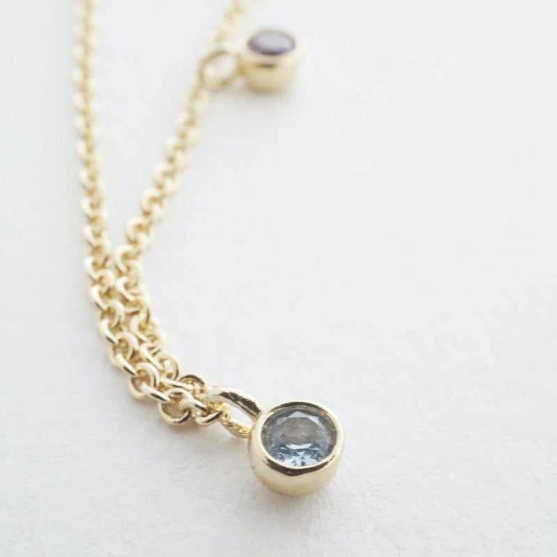 A close-up of a pale blue crystal on the necklace.