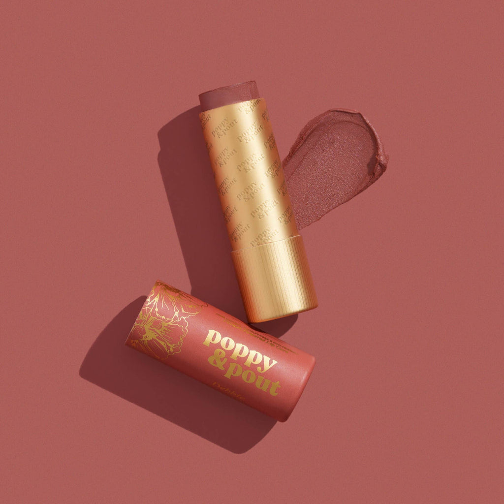 A dark peachy Debbie lip tint next to its cap and a swatch against a similarly colored background.