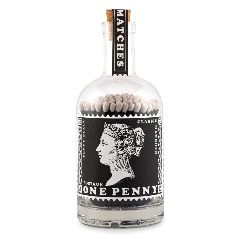 A glass corked bottle illustrated with the Penny Stamp on its label and filled with black stemmed matches .