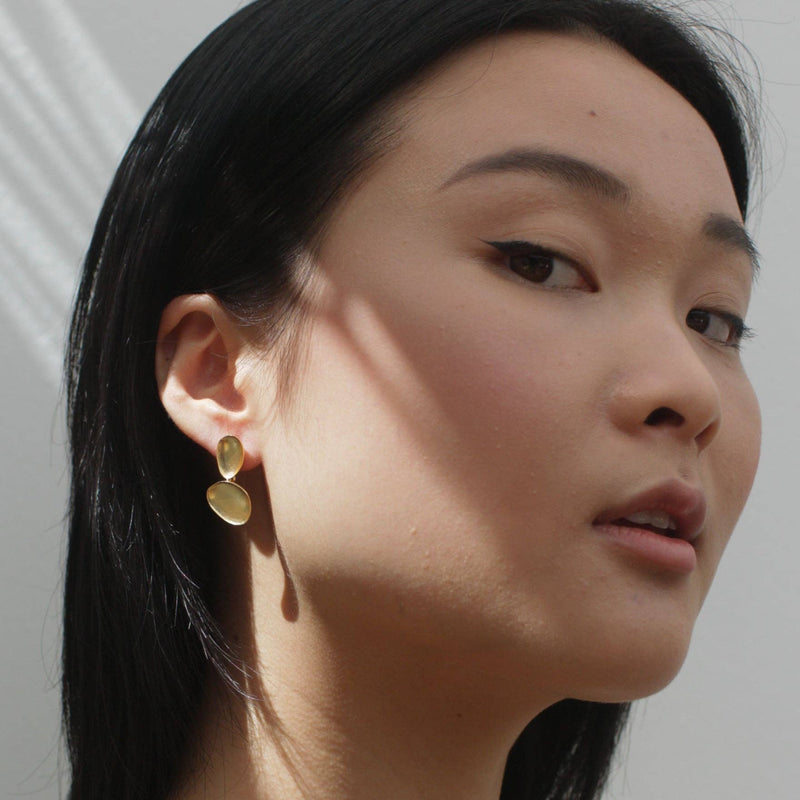 A person wearing the Luxe Gold Baubles Earrings with a ray of sun across the ear.