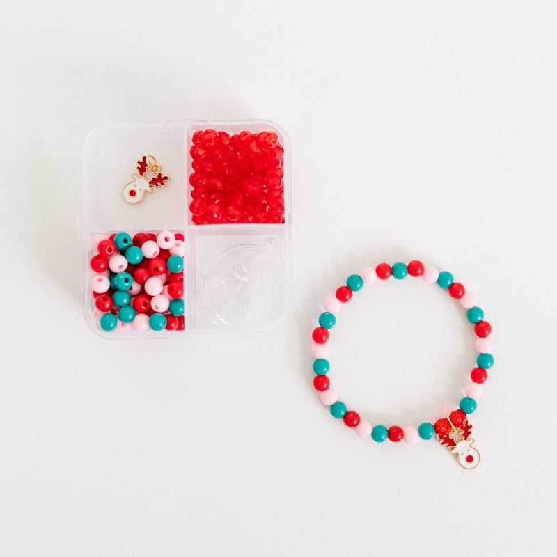 A storage container filled with red, green, and pink beads, a reindeer charm, and stretch cord.