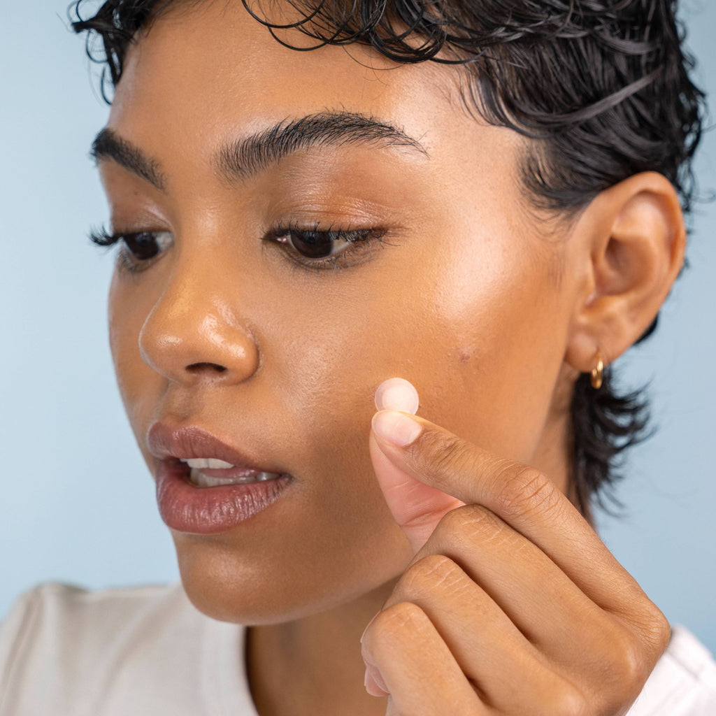 A person applying a Derma Dot patch.