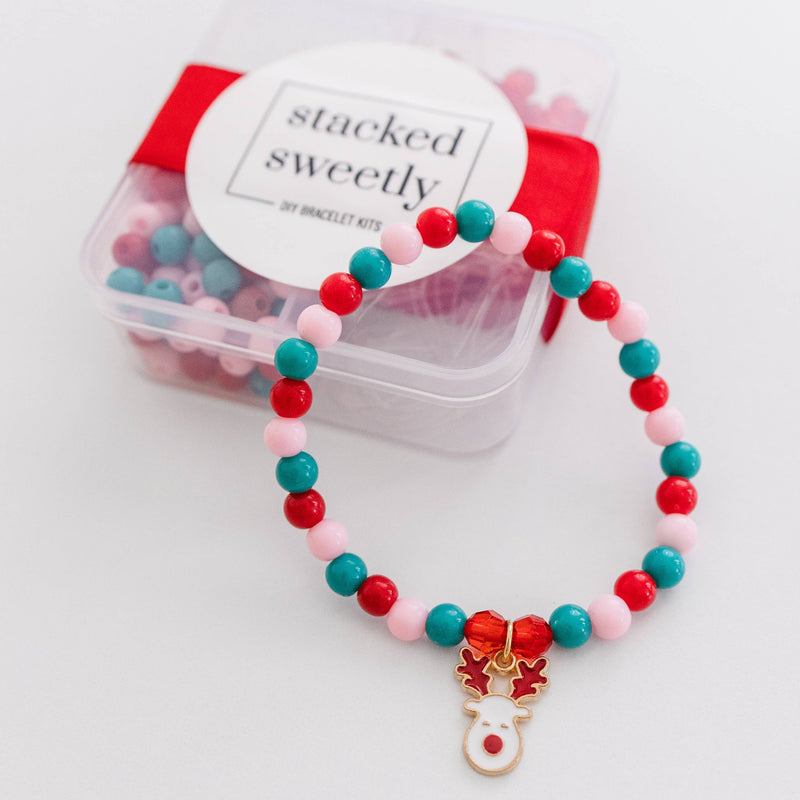 A red, pink, and green beaded bracelet with a reindeer charm resting on its DIY Kit.