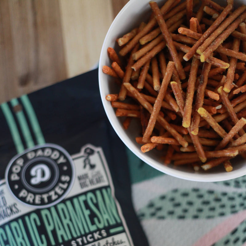 A bowl of garlic parmesan pretzels next to its bag.