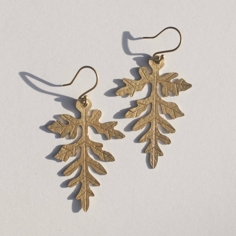 Two gold colored brass ferns hanging from fish hook earring closures.