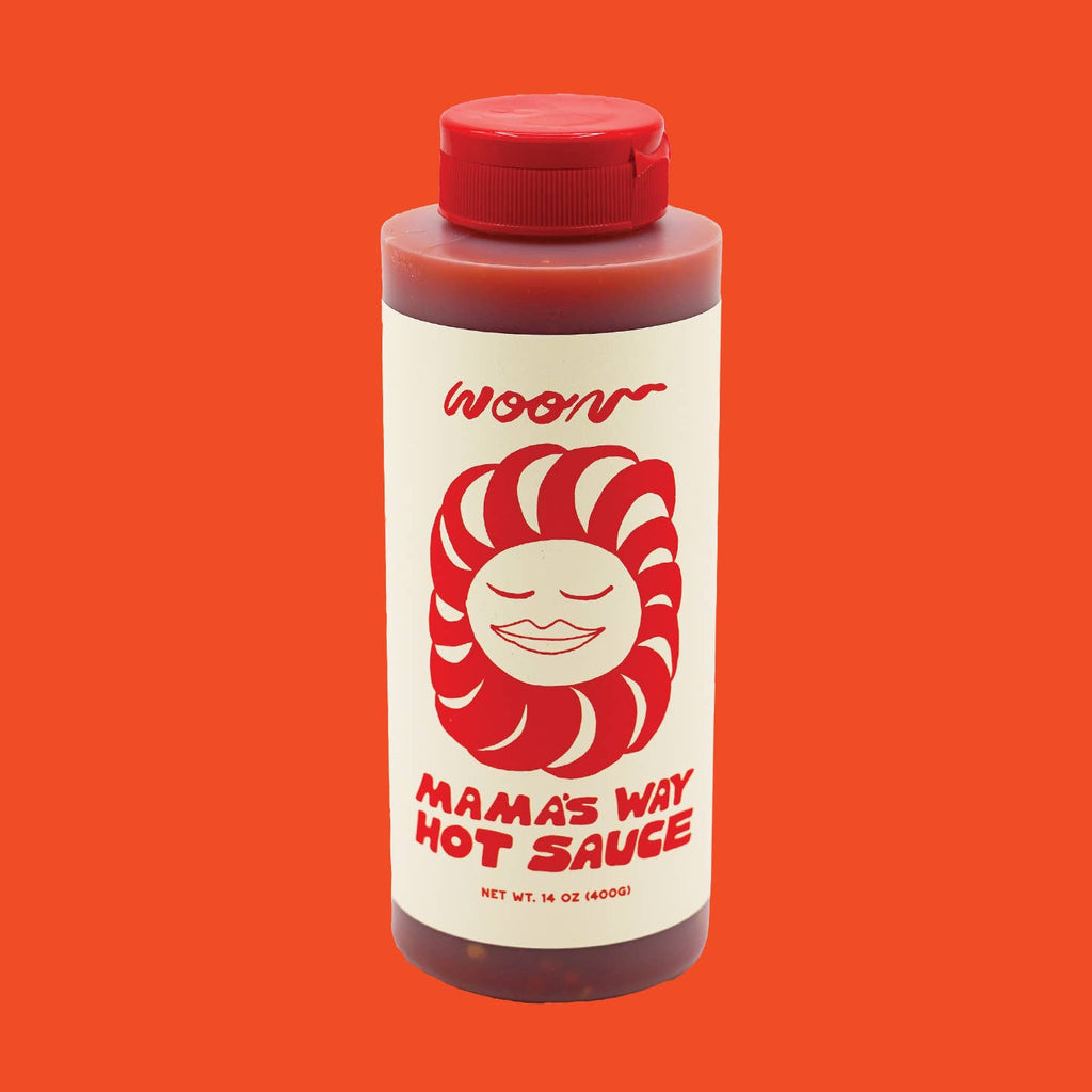 A bottle of Woon Mama's Way Hot Sauce with a red cap and a label illustrated with a smiling face.