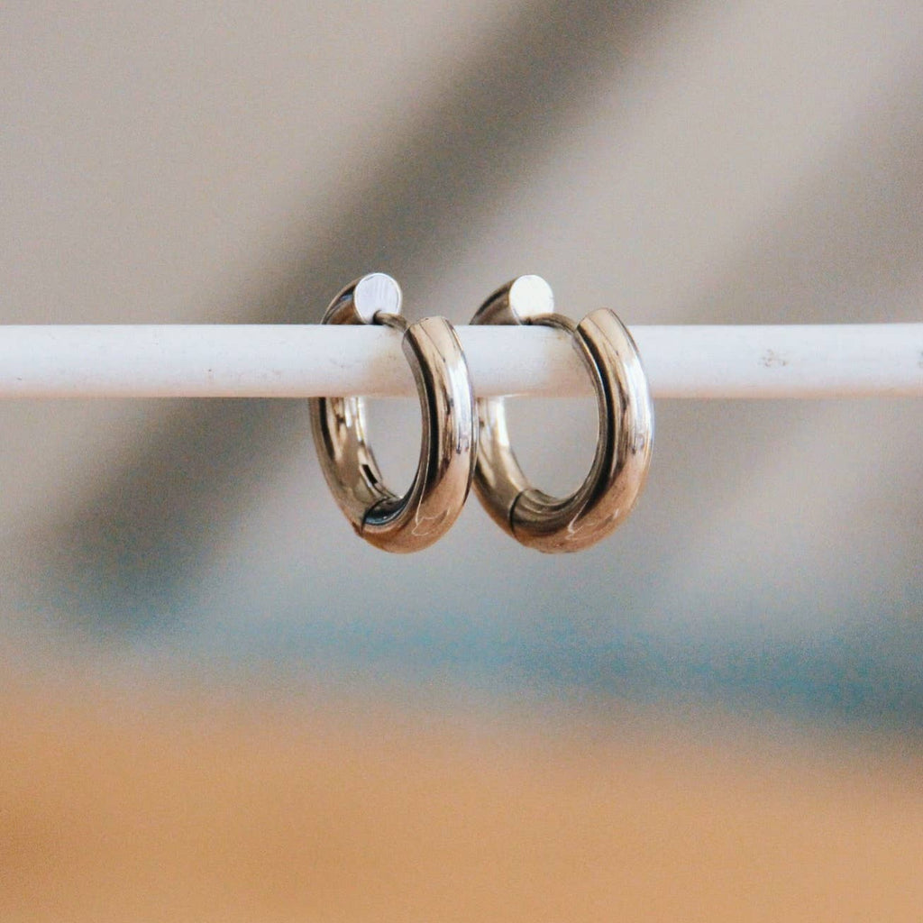 Two thick silver hoops that hug close to the ear and close with a hinged closure.