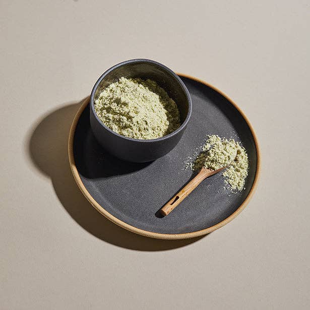 A ceramic bowl of Taylor Street Garlic & Herb seasoning with a wooden spoon spooning it out onto a ceramic plate.