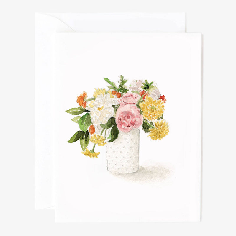 A white notecard illustrated with pink, white, orange, and yellow flowers in a white vase with a white envelope behind.