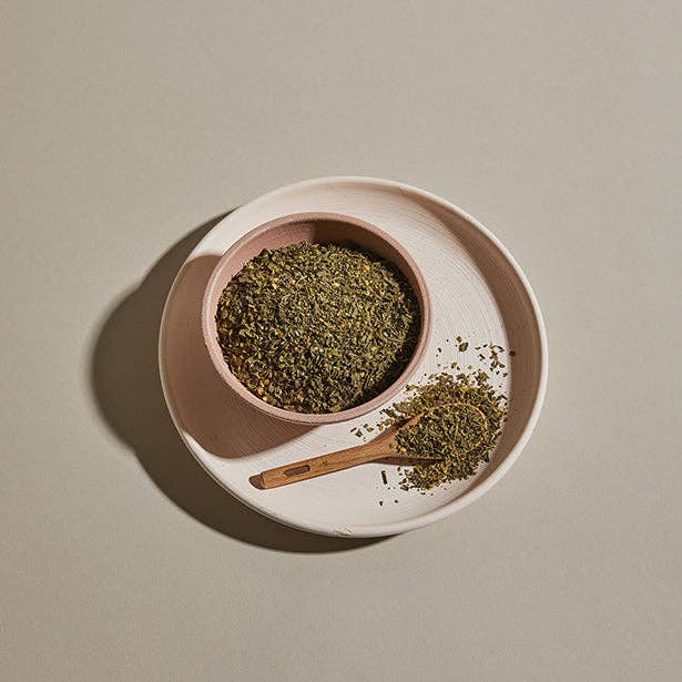 A ceramic bowl and wooden spoon filled with the Little Italy Herb Blend.