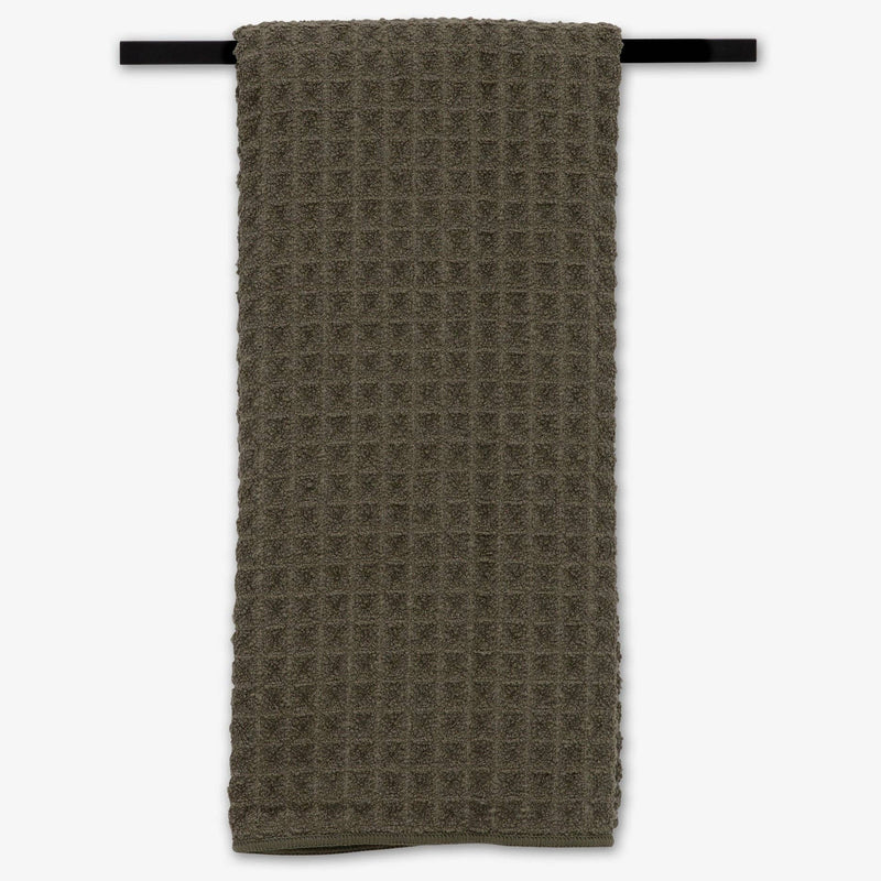 The Forest Waffle Hand Towel hanging from a towel rack.