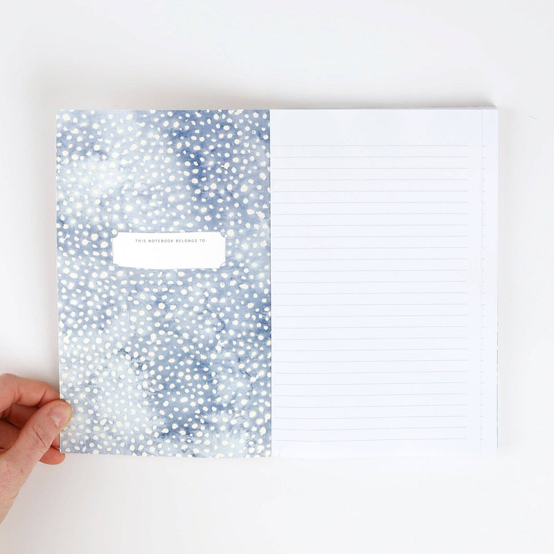 The inside front cover with white dots on blue watercolor painted background and a place to write the notebook owner's name. The opposite side is white lined paper.