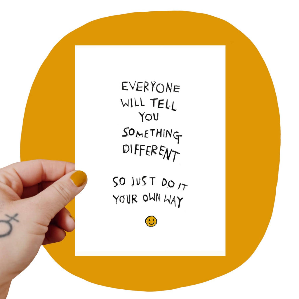 A manicured hand holding a white print that says "Everyone will tell you something different, so just do it your own way." with a yellow smiley face below.