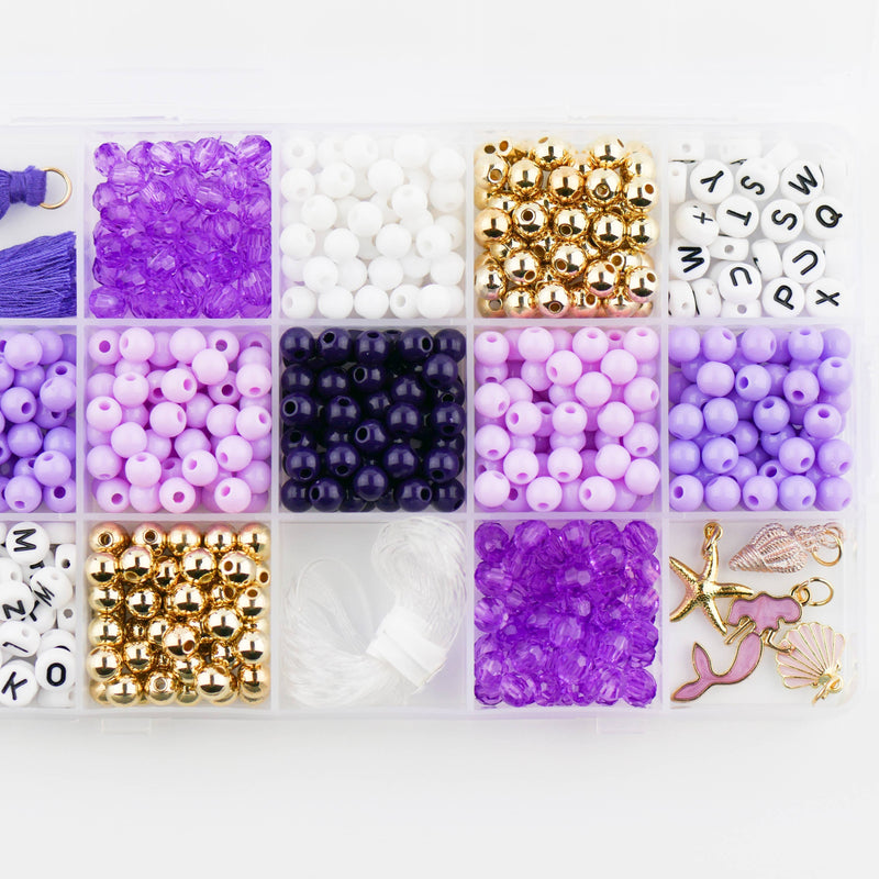 A storage box filled with purple, white, and gold beads and mermaid charms.