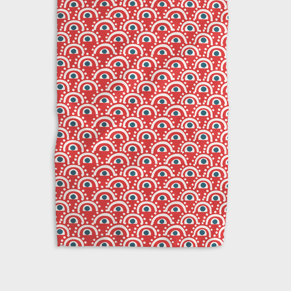 A red tea towel patterned with abstract white and blue eyes.